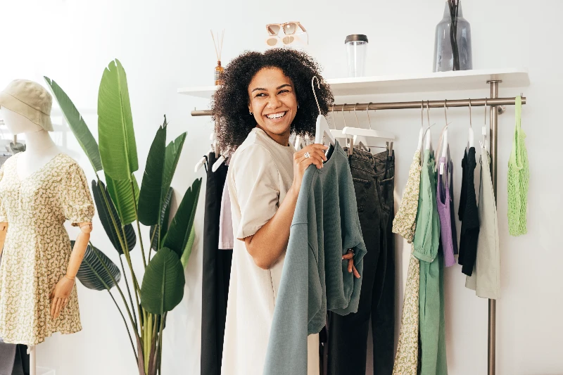 Laughing woman customer choosing sweater in store